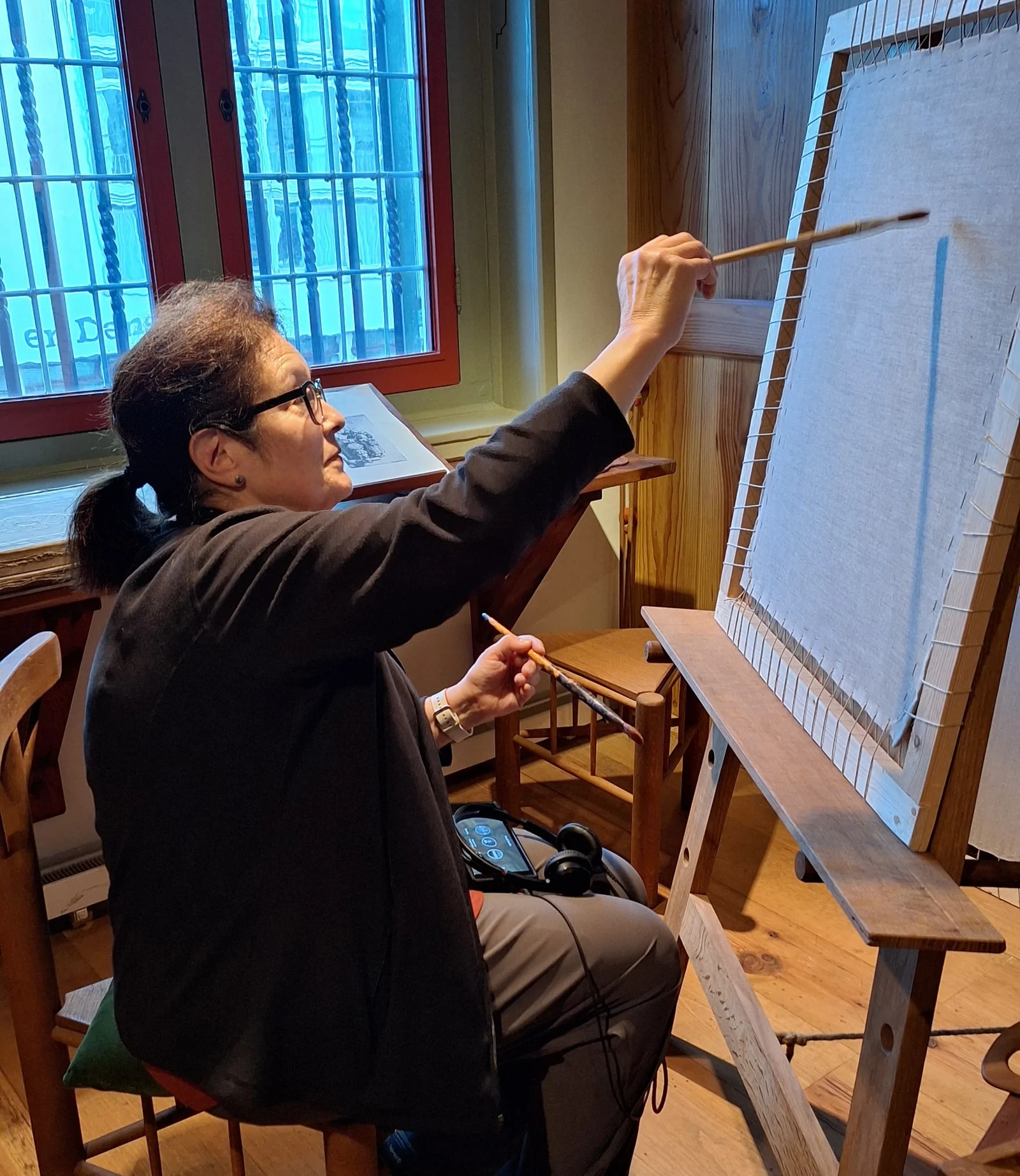 Frances Catania, Hudson Valley artist, at her painting easel in the studio — author of Café Girls Volume 1